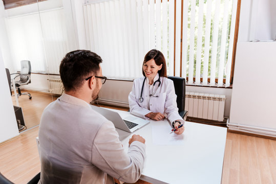 Doctor And Patient Sitting At A Table Talking In A Office