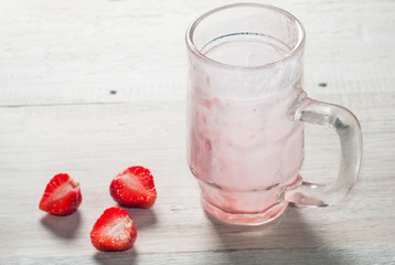 Empty strawberry smoothie Cup with a straw on a white wooden background,
