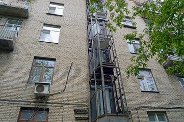 Монтаж шахты внешнего лифта на стене старого пятиэтажного трёхподъездного кирпичного жилого дома в Москве