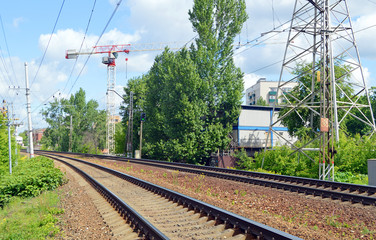 Поворот железнодорожных путей и строительный башенный подъемный кран на заднем плане