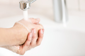 A woman washing her hands under running water from the crane