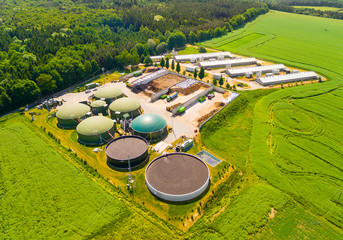 Aerial view over biogas plant and farm in green fields. Renewable energy from biomass. Modern...