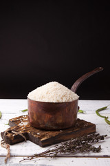 Rice in iron stewpan with green beans on wooden cutting plank. Black background for text