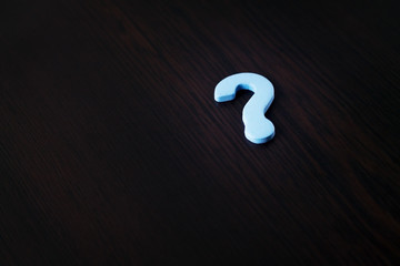 Question mark on brown wood.