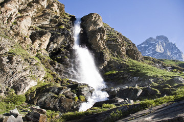 l'acqua della cascata irrompe nella valle con sullo sfondo il cervino