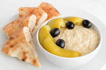 salad of baked aubergine, yogurt, and garlic dressed with lemon juice and decoreted with pepper and olives served with flatbread