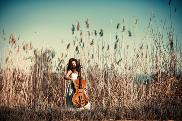 Girl with a cello in a tall grass