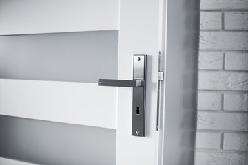 White door with metal shiny handle in modern house.