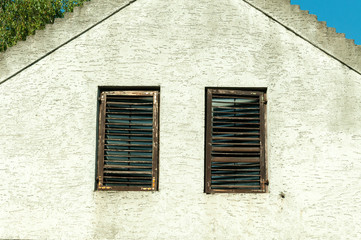 Fototapeta na wymiar Old blinds on old windows on abandoned house.