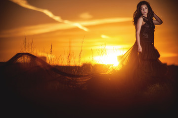 Girl in long dress on sunset background