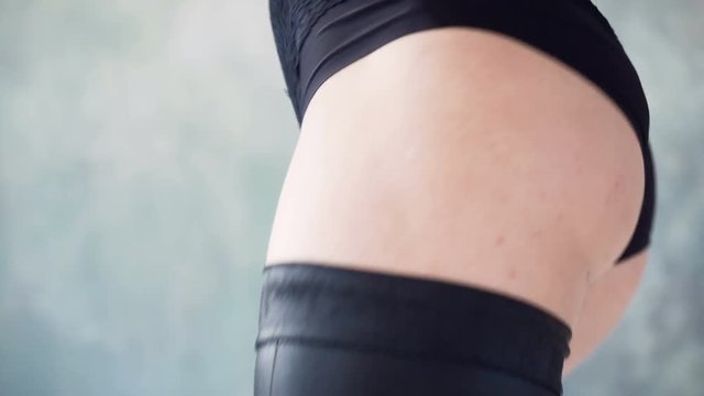 Energetic movements of female beautiful fit thighs during dance twerk dressed in black body suit in studio hall
