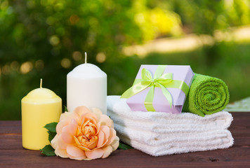 Stack of soft towels, fragrant rose, a candle and a small box with a gift. Spa concept. Romantic concept.