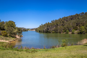 Fototapeta premium a view of blue Lac de Cavayere, artificial lake near Carcassone with green vegetation 