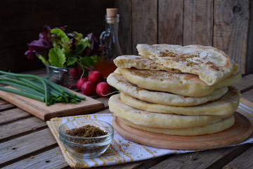 Pile of homemade flat bread with lettuce, onion and radish on a wooden background. Mexican flatbread taco. Indian Naan. Space for text