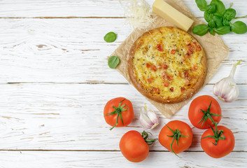 Baked flat bread with tomatoes, cheese, garlic and Basil on a white wooden table. Rustic style. Top view, copy space