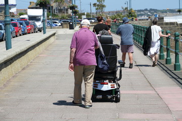 A Retired Couple (One in an Electric Wheelchair) Go Along a Prom © Alex