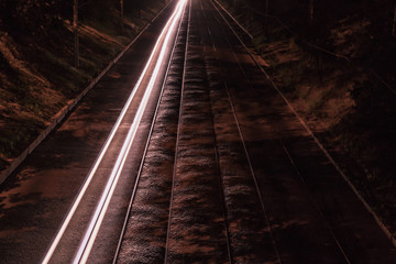 Fototapeta na wymiar Tram railway next to the track from the headlights of the car. Night scene