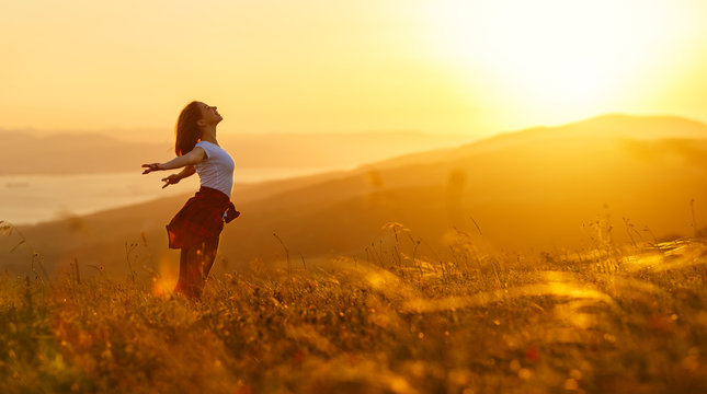 Happy woman   on the sunset in nature in summer with open hands
