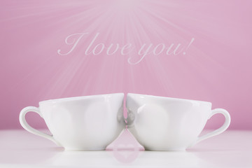 A kiss of two cups with coffee on a pink background. I love you