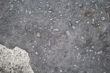 Grey asphalt with paint stain and stones texture. Cement wall with stains and grit closeup.