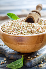 Green buckwheat with wooden scoop in bowl.