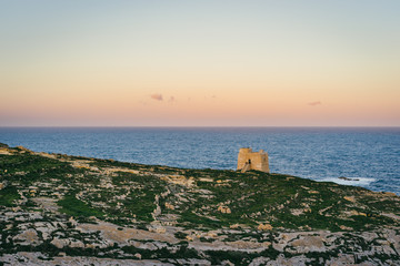 Island of Gozo, Malta. Dwejra Bay at sunrise with small watchtower