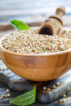 Green buckwheat with wooden scoop in bowl.