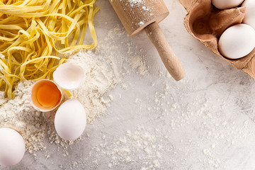 Tasty fresh appetizing raw pasta with flour and eggs on wooden old table. Top View. - obrazy, fototapety, plakaty