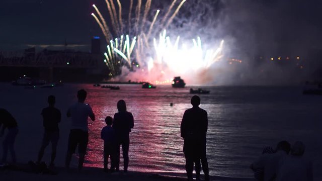 people silhouettes on a background of fireworks. group of people enjoying the city night view and fireworks