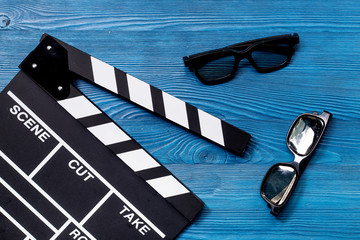 Attributes of film director. Movie clapperboard and sunglasses on blue wooden table background top...