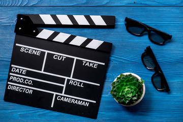 Attributes of film director. Movie clapperboard and sunglasses on blue wooden table background top...