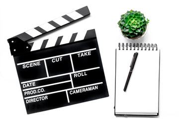 Work table of producer. Movie clapperboard and notebook on white background top view