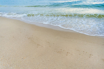 Fototapeta na wymiar background image - blue and green waves crashing on the sandy shore