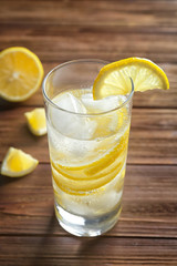 Glass of cold lemon water on wooden table
