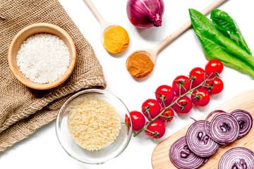 rice, spices and vegetables for paella on white desk background top view