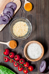 paella home cooking with rice, tomato, onion and spices for ingredients on wooden background top view space for text