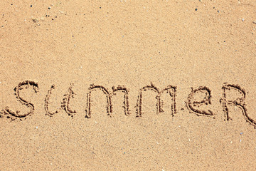 Word SUMMER written on beach sand. Vacation concept