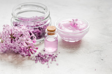 Obraz na płótnie Canvas take bath with lilac cosmetic set and blossom on stone table background