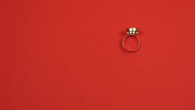 Two wedding rings roll on a red background and clash. Slow motion