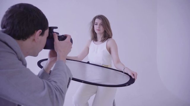 The model holds a light reflector on a photo shoot in the studio