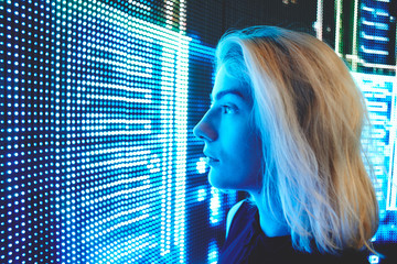 The concept of a digital future. Young blonde girl looking at the led screen closeup.