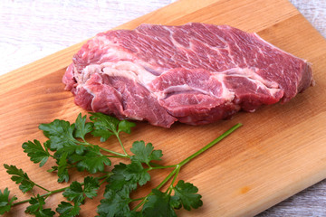 Raw beef steak with spices Leaves of coriander on wooden cutting board. Ready for cooking.