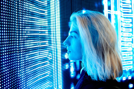The concept of a digital future. Young blonde girl looking at the led screen closeup.