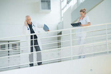doctor nd nurse in hospital corridor resting against balcony