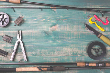 Fishing rods, fishing tackles, lines, knife and feeders on green wooden background with free space