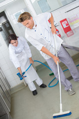 restaurant employees cleaning the kitchen floor