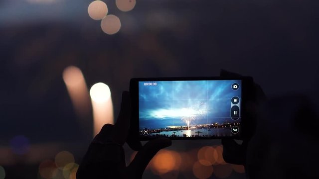 woman shoots fireworks on a mobile phone. hands of woman taking the photo to fireworks with the smartphone