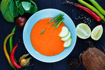 Traditional thai tom yam soup with vegetables, served in bright plate, decorated with physalis, coconut, rambutan, chili peppers,sesame,lime and spices, delicious thai cuisine