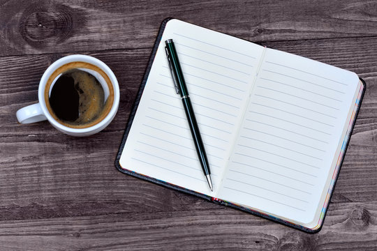 Empty notebook with coffee cup on wooden background