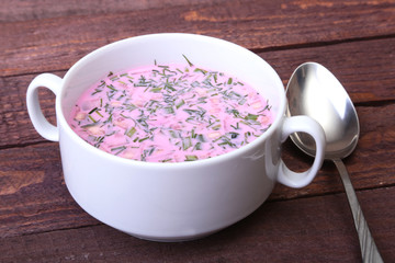 Popular spring cold soup okroshka with yoghurt. Okroshka in a bowl and slices bread on wooden table. Selective focus